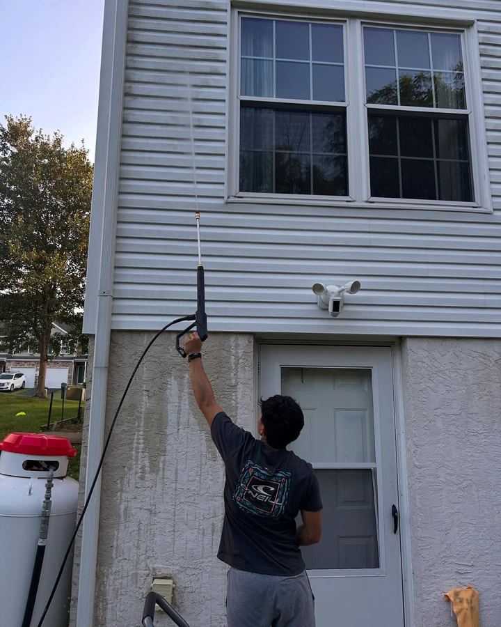 Transparency Tribe crew member power washing second-story siding